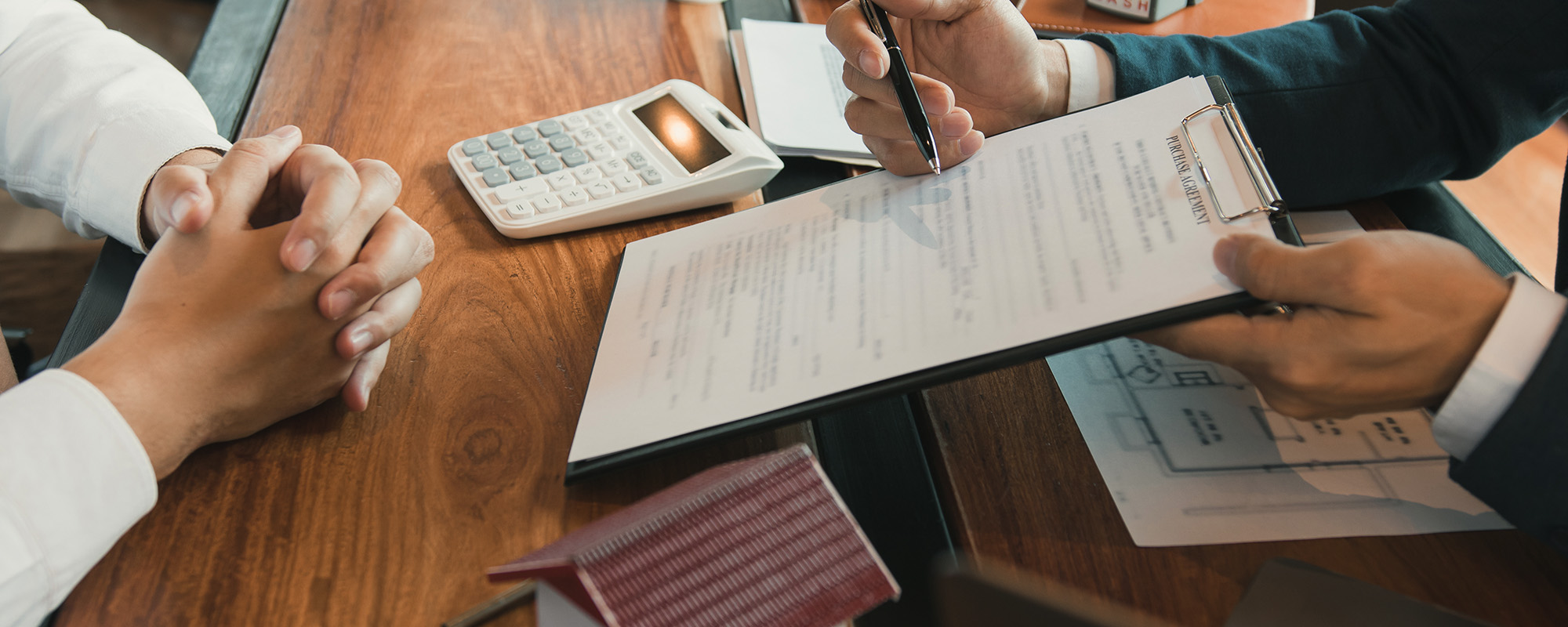 Agents are using pens pointing to contracts and are being explained to customers at the office.